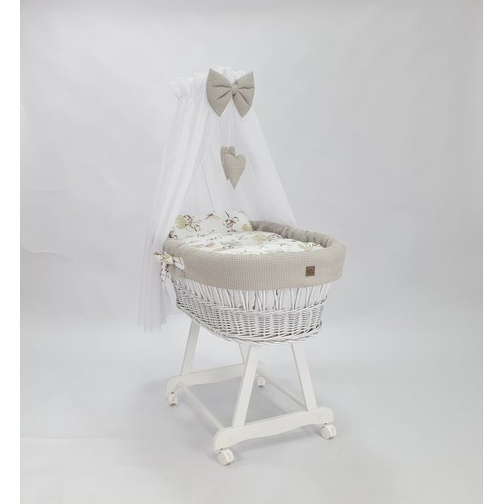Weißes Korbbett mit Babyausstattung – Baumwollblumen